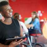 Smiling Woman working on tablet in front of red wall