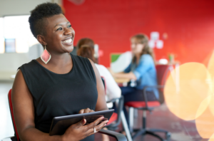 Smiling Woman working on tablet in front of red wall